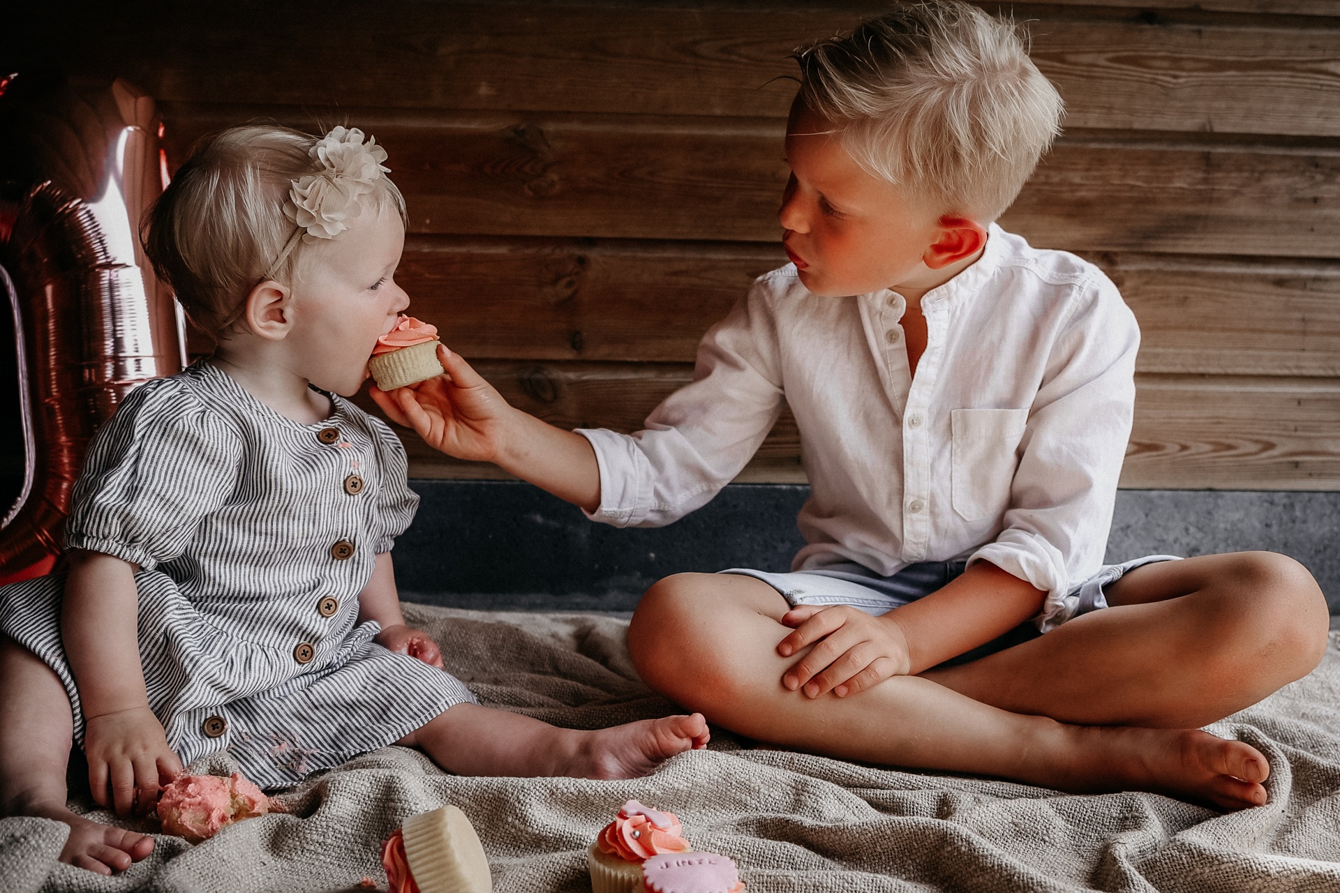 Cakesmash foto van een meisje met haar broer die een cupcake eten.