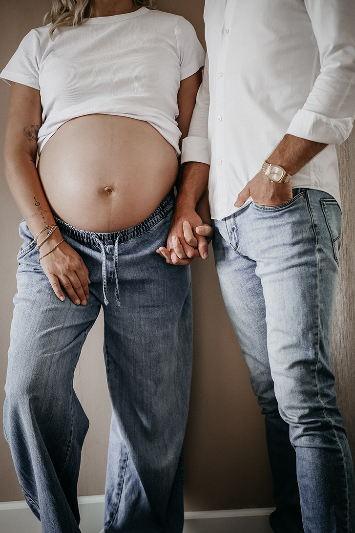 Foto van een stelletje, zwangere buik in wit shirt en jeans.