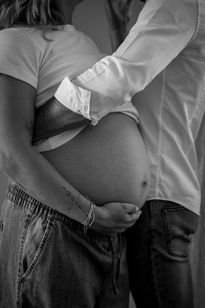 Zwart wit foto van een zwangere buik die wordt vastgehouden door partner.