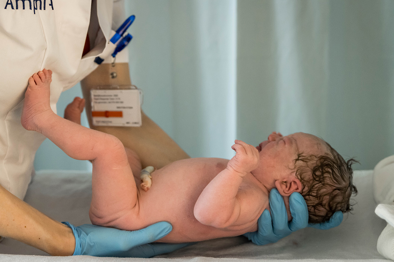 Foto van pasgeboren baby die vastgehouden wordt door verpleegkundige, geboortefotograaf, Amphia ziekenhuis
