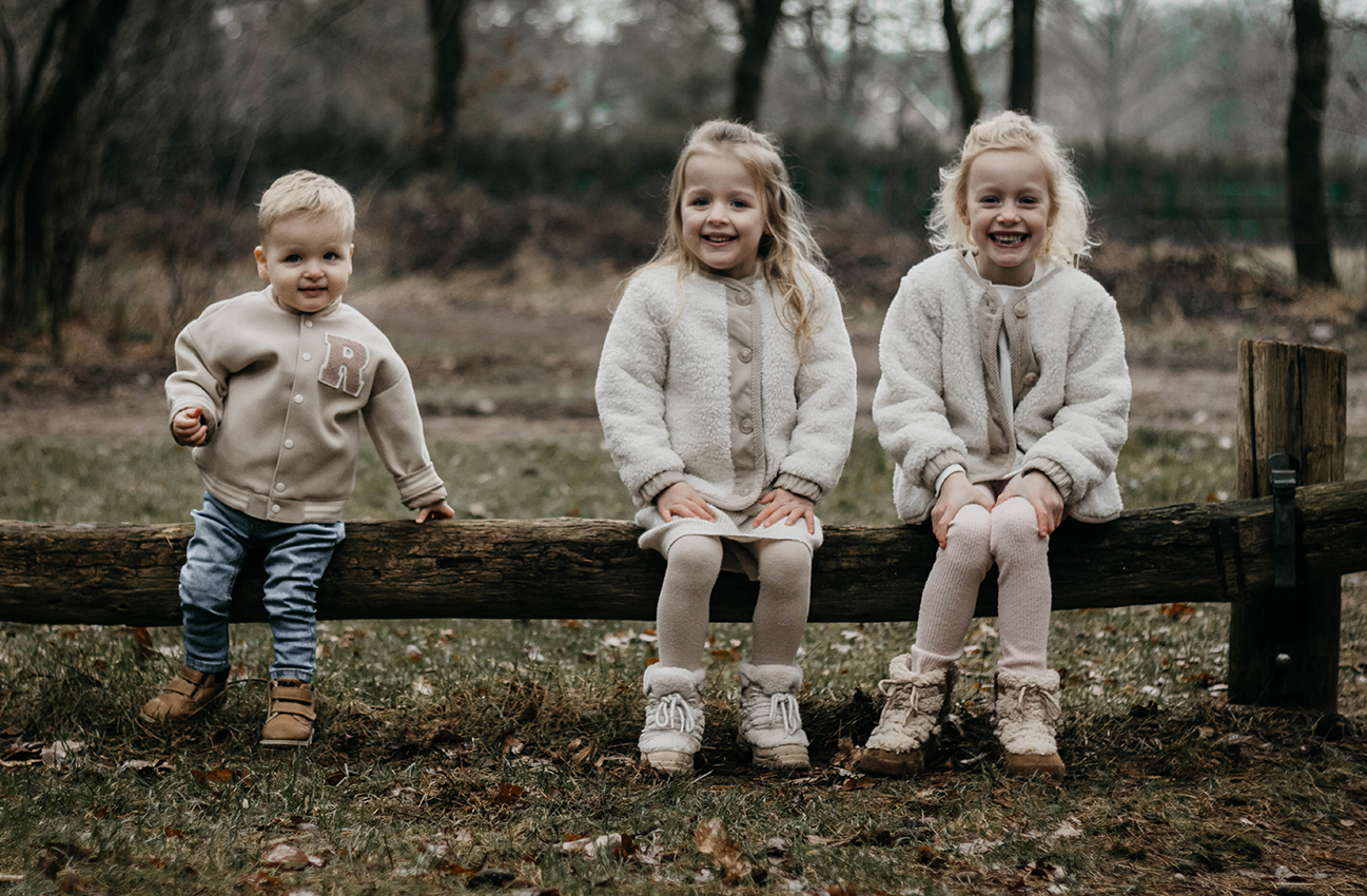 Foto van drie kinderen op een hekje in het bos, gezinsshoot, Loonse duinen